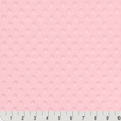 The image is a close-up of a pink fabric with a textured surface, and there is a ruler at the bottom of the image for scale.