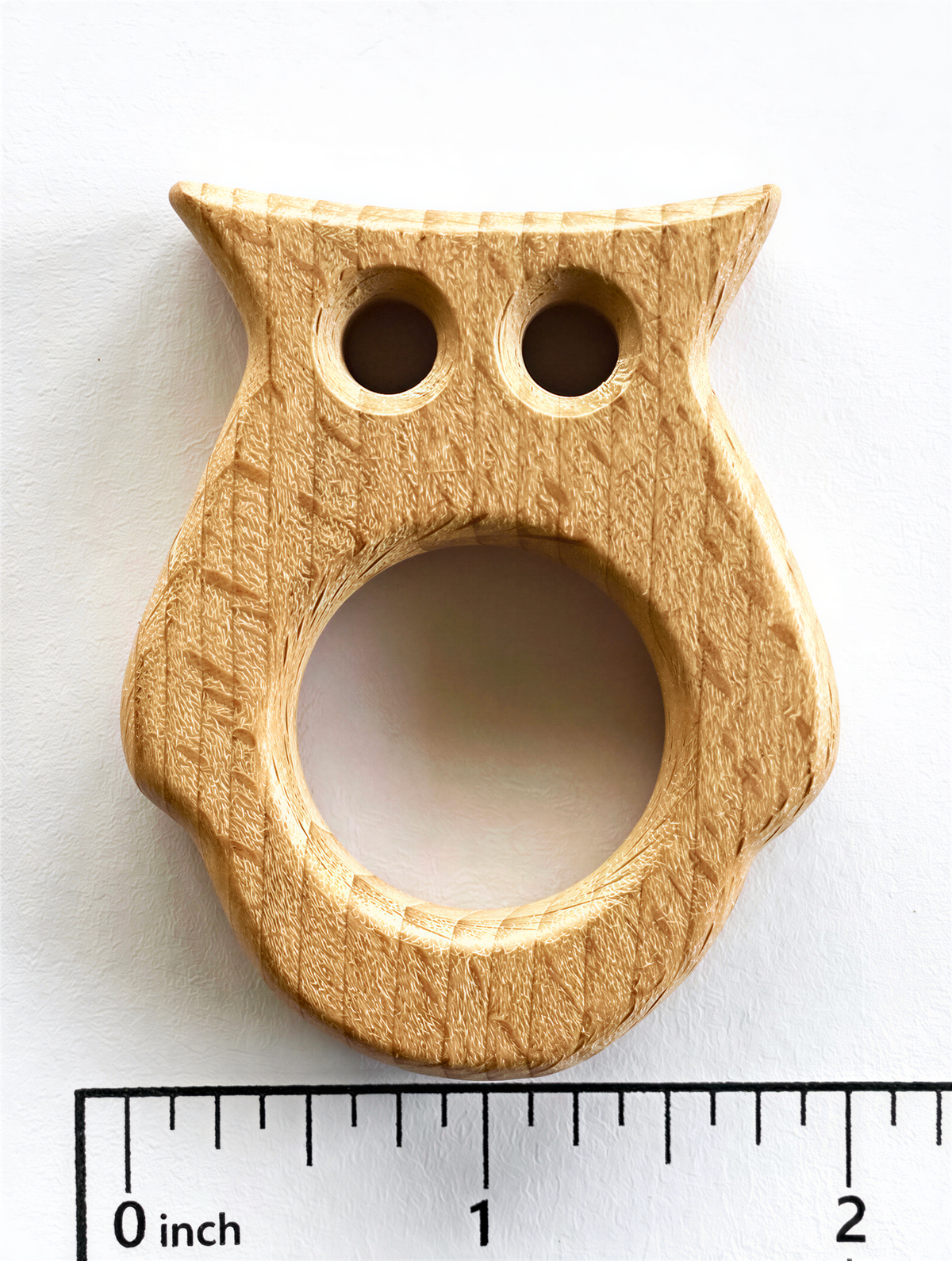 A wooden owl-shaped object is shown next to a ruler for size comparison.