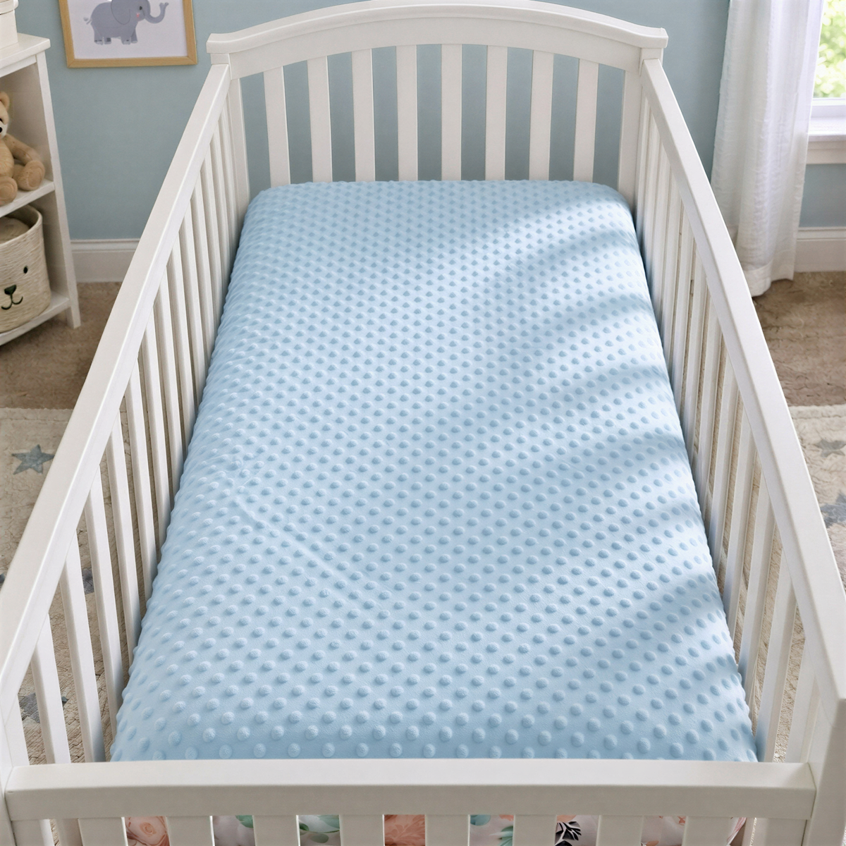 A white crib with a blue mattress in a nursery.
