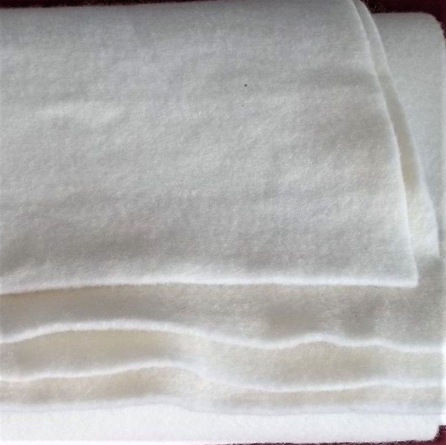 A close-up image of a pile of white, fluffy material, possibly a soft fabric or a pile of cotton balls.
