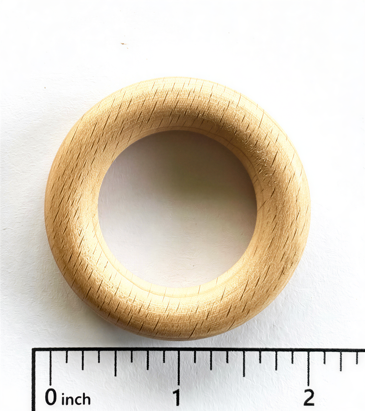 A wooden ring is shown next to a ruler for size comparison.