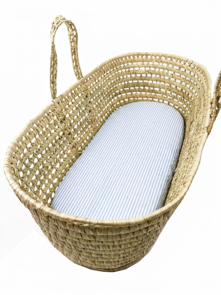 A woven basket with a blue and white striped mattress inside.