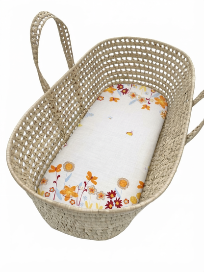 A woven basket with a floral pattern on the side and a white sheet with a floral pattern inside.
