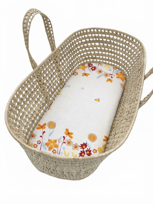 A woven basket with a floral pattern on the side and a white sheet with a floral pattern inside.