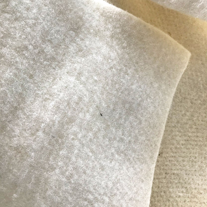 a close-up view of a white, fluffy material, possibly a piece of fabric or a soft, fluffy material. There is a small black speck or speck of dirt on the surface, which is the only noticeable detail in the image.
