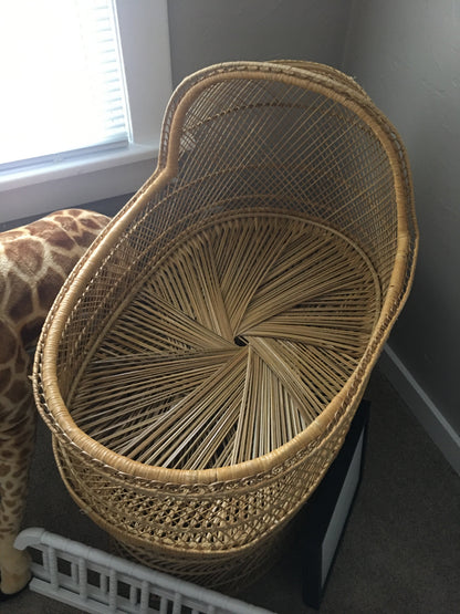 A woven basket with a unique spiral pattern sits on a carpeted floor next to a window.